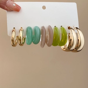 Close-up of a 6-pair gold and resin hoop earring set displayed on a white hanging card