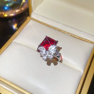 Close-up of luxury flower ring with a large ruby red stone and silver butterfly accents