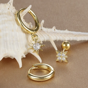 Detailed view of three gold star earrings with cubic zirconia on a white seashell