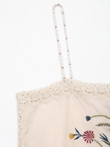 Close-up of floral embroidery and delicate lace details on knit camisole set