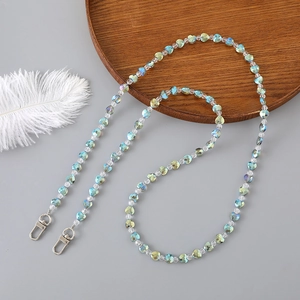 Blue and green crystal beaded crossbody chain with silver metal clasps on a wooden tray