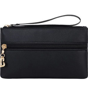 Detail of black leather clutch with golden zippers and C-shaped metal pendant charm