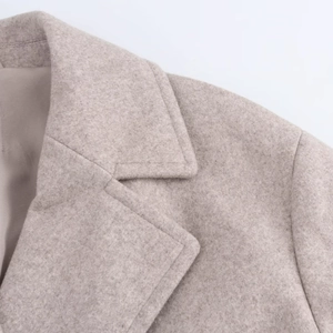 Close-up of the lapel and shoulder seams on a wool coat in beige oat color
