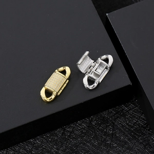 Macro detail of gold and silver cuban clasp with zircon stones in open and closed views
