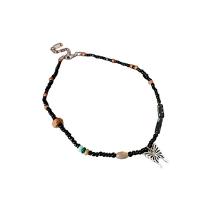 Ethnic ceramic necklace with black beads and a silver butterfly pendant on white background