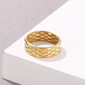 Macro detail of a gold titanium steel ring with quilted diamond patterns on a stone block