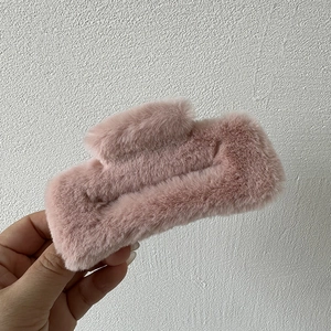 Detail of plush rectangular hair claw clip in soft pink faux fur for autumn winter styling