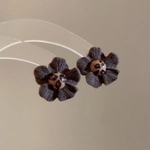 Detailed macro view of dark grey suede flower earrings with leopard print bead center