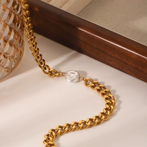 Detailed close-up of a gold Cuban chain necklace featuring a single white round pearl pendant