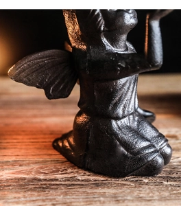 Macro shot of vintage cast iron kneeling angel sculpture with matte black metal texture