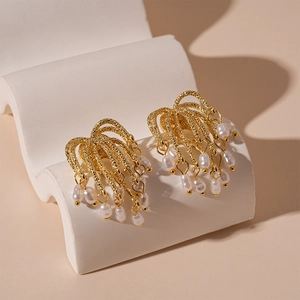 Gold metallic firework earrings with pearl fringe tassels on white decorative base