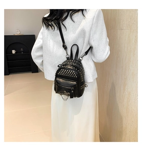 Detail of black mini PU leather backpack with silver rivets and metal cross pendant chain
