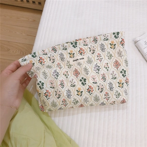 Detailed close-up of a floral cotton makeup bag with a simple wish tag held by hand