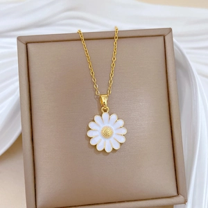 Detailed shot of golden daisy necklace with white petals in a premium gift box