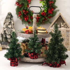 Mini green Christmas trees with red plaid burlap base on a wooden tray for festive decor
