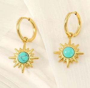 Macro shot of 18K gold starburst earrings with turquoise center on white fabric