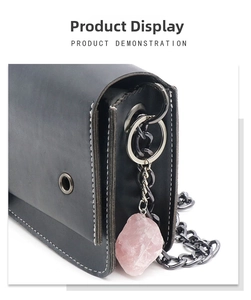 Detail of pink natural stone pendant and metal chain on black leather crossbody bag