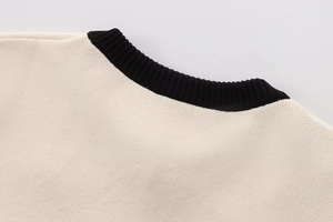 Close-up of contrast crew neck detail on cream-white knit sweater with black ribbed collar