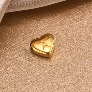 Macro shot of a gold heart-shaped bead with letter A engraving for DIY jewelry