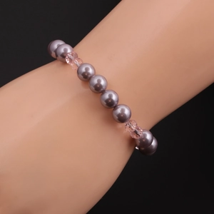 Elegant beaded bracelet with grey pearls and pink crystals on a display arm