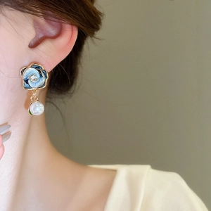 Macro shot of a blue flower earring with a dangling pearl and sparkling center crystal