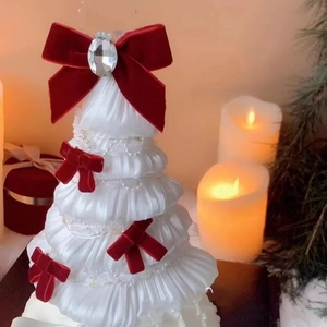 Detail of handmade white fabric Christmas tree with red velvet bows and pearl chains