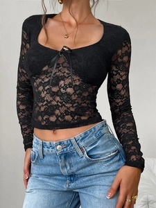 Détail d'un haut en dentelle noire à fleurs avec des lacets décoratifs sur le devant