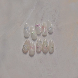 Handcrafted long almond press-on nails with pastel bows, pearls, and crystal rhinestones