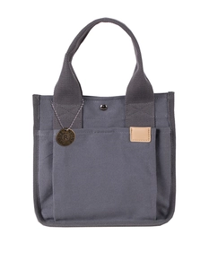 Detalle del bolso de lona gris oscuro con colgante metálico y costuras finas