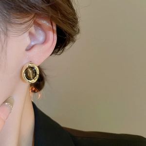 Close-up of vintage gold plated earrings with brown tiger eye stone on model's ear