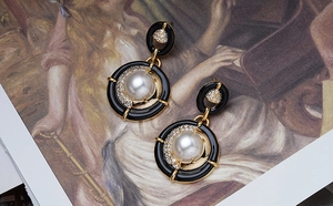 Détail de boucles d'oreilles perles rétro avec émail noir sur une peinture à l'huile