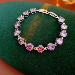 Detailed close-up of purple round zircon bracelet on green velvet background