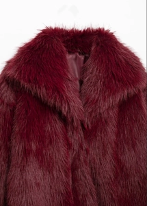 Détail d'un manteau en fausse fourrure bordeaux montrant la texture du revers