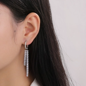 Close-up of dangling silver tassel earrings with clear square-cut rhinestones on model