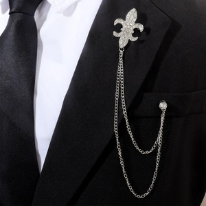 Détail d'une broche lys en argent avec chaînes et strass sur le revers d'un costume noir