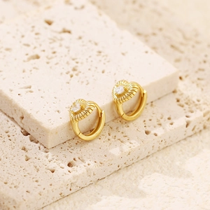 Macro view of gold heart huggie earrings with vertical texture and clear zircon stone