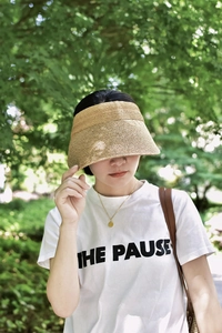 Detail of high-density raffia sun visor hat worn outdoors in natural sunlight