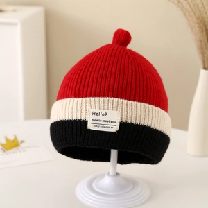 Close-up of color-blocked knit baby hat with striped design and woven brand label