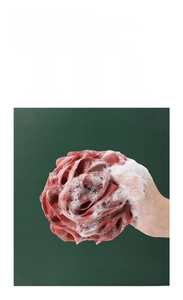 Detail showing dense mesh texture of a dark red bath sponge generating rich white foam
