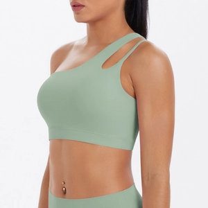 Detail view of sage green asymmetrical one-shoulder sports bra with cutout strap detail
