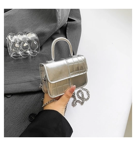 Close-up of silver mini handbag featuring a metallic crocodile texture and chain strap
