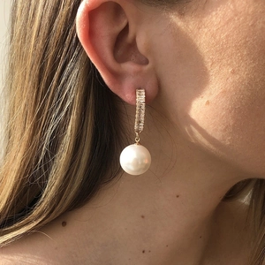 Close-up of vintage gold earrings featuring rectangle zircons and a large white pearl drop