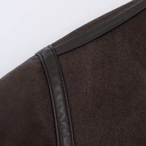 Detailed view of dark brown faux suede jacket featuring leather piping and stitching