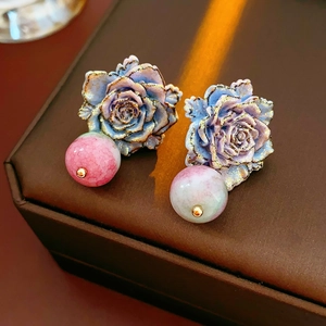 Détail macro de boucles d'oreilles rose avec pétales dégradés bleu-violet et dorés
