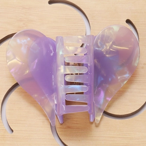 Macro view of pearlescent marble purple heart-shaped hair claw on wooden background