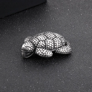 Macro view of vintage turtle pendant with detailed dot texture and silver metal finish