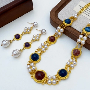 Macro shot of vintage gold necklace and pearl drop earrings set with colorful beads