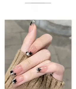 Detail of nude press-on nails with silver glitter French tips and black star patterns