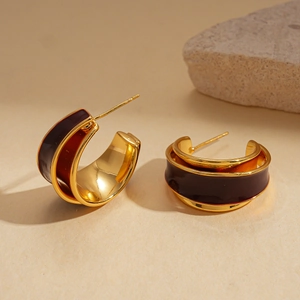 Detailed close-up of 18k gold-plated C-shape earrings with dark red enamel inlays
