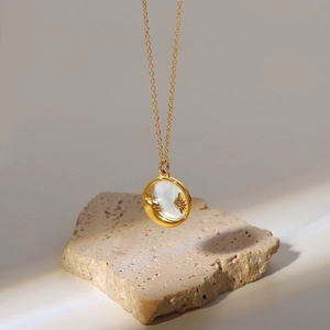 Detail of 18K gold stainless steel necklace with white shell moon and star pendant
